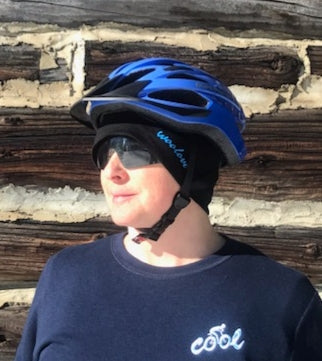 100% merino wool beanie by Wool Love is worn by cyclist under helmet. This person has a small head so the OS sized beanie can be pulled down below her ears + top of safety glasses for wind protection